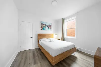 a white bedroom with a bed and a window at Modern and cozy 4 bedrooms sleep 12 in Montréal