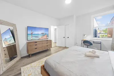 a bedroom with a bed and a dresser with a television at Modern and cozy 4 bedrooms sleep 12 in Montréal