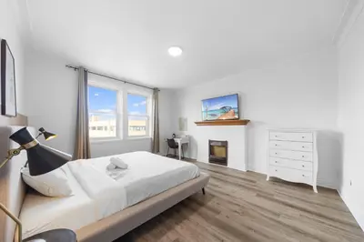 a white bedroom with a bed and a fireplace at Modern and cozy 4 bedrooms sleep 12 in Montréal