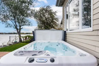 a hot tub sitting on the side of a house at Modern Lake Champlain Villa with Spa in Venise-en-Québec