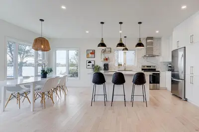 a white kitchen with a dining table and chairs at Modern Lake Champlain Villa with Spa in Venise-en-Québec