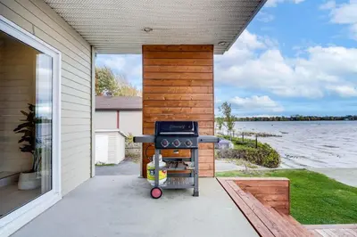 a grill on a patio with a view of the water at Modern Lake Champlain Villa with Spa in Venise-en-Québec