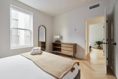 a white bedroom with a bed and a mirror at New and Cozy 3 bedroom in Le Plateau by Denstays in Montréal