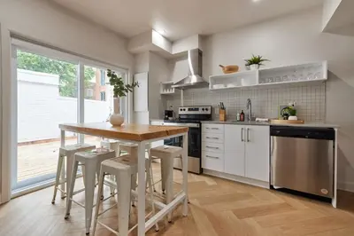 a kitchen with white cabinets and a wooden table with stools at Spacious 2 bedroom apartment in Le Plateau by Denstays in Montréal