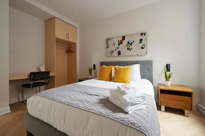 a bedroom with a large white bed with yellow pillows at Urban Gem in Le Plateau by Denstays in Montréal