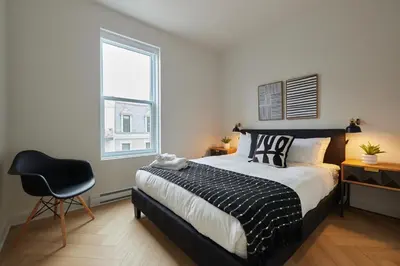 a bedroom with a bed and a chair and a window at Urban Gem in Le Plateau by Denstays in Montréal