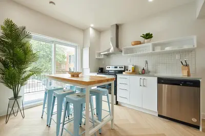 a kitchen with a table and some blue stools at Urban Gem in Le Plateau by Denstays in Montréal