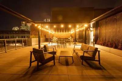 a rooftop patio with chairs and a table with lights at Downtown Montreal Premium Cozy Studio in Montréal