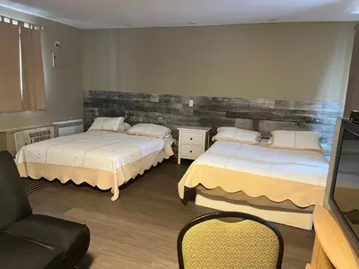 a bedroom with two beds and a chair and a television at Motel la siesta de gascon in Terrebonne