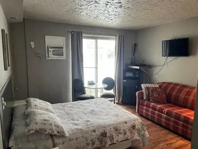 a room with a bed and a couch and a window at Motel la siesta de gascon in Terrebonne