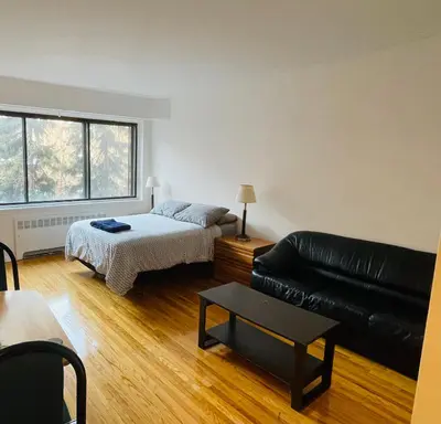 a living room with a bed and a black leather couch at Stylish Montreal Apartment: Comfortable Stay in the Golden Square Mile in Montréal