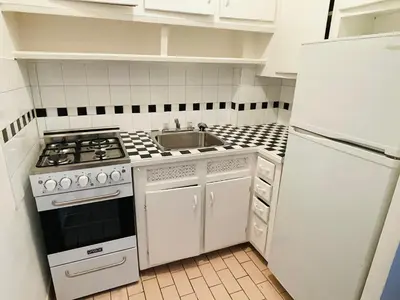 a white kitchen with a stove and a sink at Stylish Montreal Apartment: Comfortable Stay in the Golden Square Mile in Montréal
