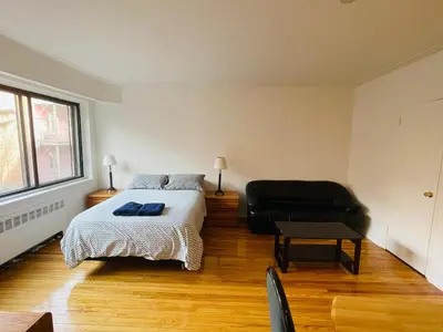 a bedroom with a bed and a black chair at Stylish Montreal Apartment: Comfortable Stay in the Golden Square Mile in Montréal