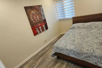 a bedroom with a bed and a painting on the wall at Spacious bright Apt,Parking and self check-in in Longueuil