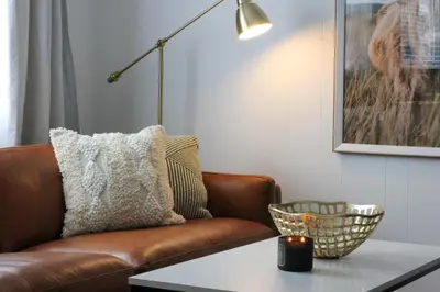 a living room with a brown couch and a table at Repère d'Eastman - Spa et Accès au lac in Eastman