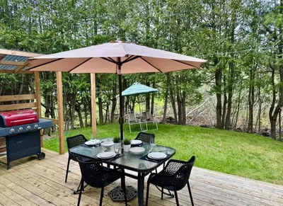 a table and chairs under an umbrella on a patio at Repère d'Eastman - Spa et Accès au lac in Eastman