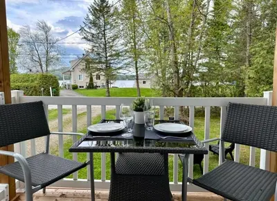 a table and chairs on a balcony with a view of a yard at Repère d'Eastman - Spa et Accès au lac in Eastman