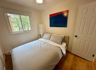 a bedroom with a white bed with a window at Repère d'Eastman - Spa et Accès au lac in Eastman