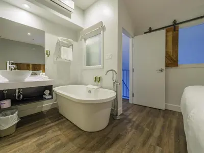 a bathroom with a tub and a sink and a bed at Hotel Lac Brome, BW Signature Collection in Lac-Brome
