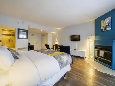 a bedroom with a large white bed and a fireplace at Hotel Lac Brome, BW Signature Collection in Lac-Brome