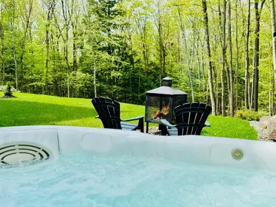 a hot tub in a yard with chairs and a lantern at Woodpecker Spa and peace in Orford