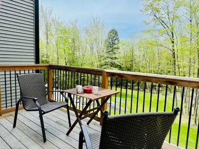 a table and two chairs on a deck with a view at Woodpecker Spa and peace in Orford