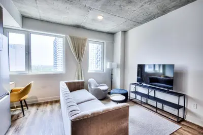 a living room with a couch and a tv at Executive Class Apartments with Gym for VIP & Students in Downtown MTL in Montréal
