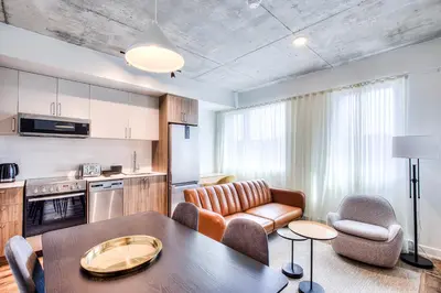 a kitchen and a living room with a table and chairs at Executive Class Apartments with Gym for VIP & Students in Downtown MTL in Montréal