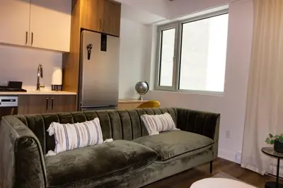a living room with a green couch and a kitchen at Executive Class Apartments with Gym for VIP & Students in Downtown MTL in Montréal