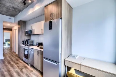 a kitchen with a white refrigerator and wooden cabinets at Executive Class Apartments with Gym for VIP & Students in Downtown MTL in Montréal