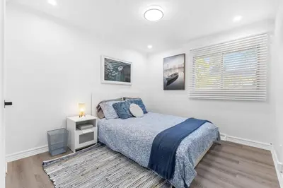 a white bedroom with a bed and a window at Spacious Urban Cabin in West Montreal - 4BR in Montréal