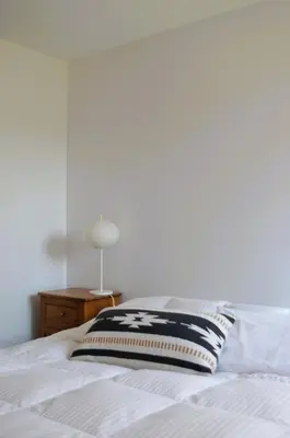 a white bed with a black and white pillow on it at Suite-appartement 2 chambres à la campagne. Rez de jardin in Dunham