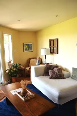 a living room with a white couch and a table at Suite-appartement 2 chambres à la campagne. Rez de jardin in Dunham