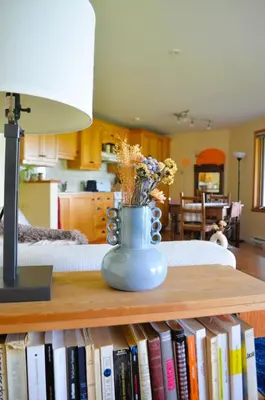 a table with a vase with flowers on top of books at Suite-appartement 2 chambres à la campagne. Rez de jardin in Dunham