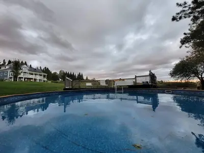 a large swimming pool in front of a house at Suite-appartement 2 chambres à la campagne. Rez de jardin in Dunham