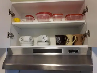 a kitchen shelf with dishes and cups in it at Appartement Cartier in Longueuil