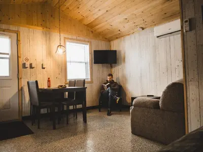 a man sitting on a chair in a room at Camping Abenaki Aventure - Les Chalets in Pierreville