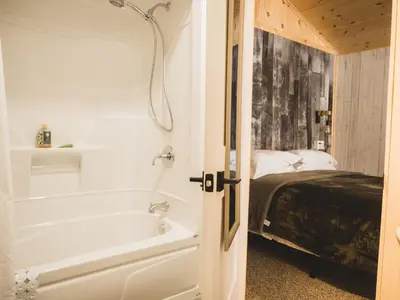 a bathroom with a bath tub next to a bed at Camping Abenaki Aventure - Les Chalets in Pierreville