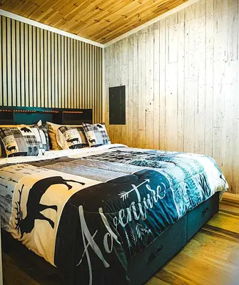 a large bed in a room with wooden walls at Camping Abenaki Aventure - Les Chalets in Pierreville