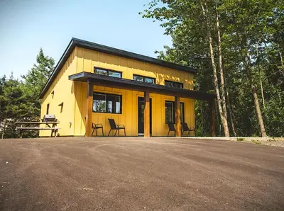a yellow house with two chairs in front of it at Camping Abenaki Aventure - Les Chalets in Pierreville
