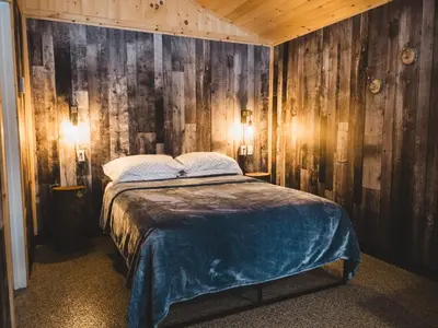 a bedroom with a bed in a room with wooden walls at Camping Abenaki Aventure - Les Chalets in Pierreville
