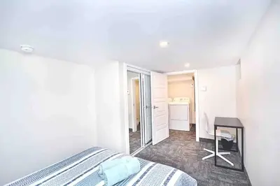a white bedroom with a bed and a table in it at Beautiful 4-BDR in Heart of Plateau Mont-Royal in Montréal