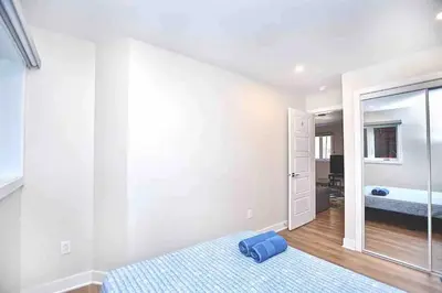 a white bedroom with a bed and a mirror at Beautiful 4-BDR in Heart of Plateau Mont-Royal in Montréal