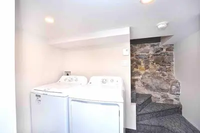 a white washer and dryer in a room with a stone wall at Beautiful 4-BDR in Heart of Plateau Mont-Royal in Montréal