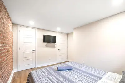a bedroom with a bed and a tv on the wall at DUPLEX 6 BEDROOMS IN HEART OF PLATEAU MONT-ROYAL in Montréal