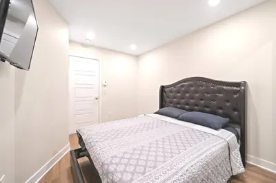 a bedroom with a bed with a black headboard and a tv at DUPLEX 6 BEDROOMS IN HEART OF PLATEAU MONT-ROYAL in Montréal