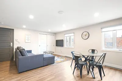 a living room with a couch and a table and chairs at DUPLEX 6 BEDROOMS IN HEART OF PLATEAU MONT-ROYAL in Montréal