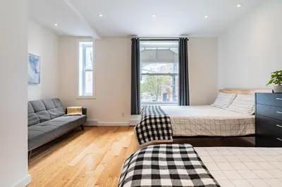 a bedroom with a bed and a couch and a window at Ideal Group Stay in Charming Le Plateau Near Metro in Montréal