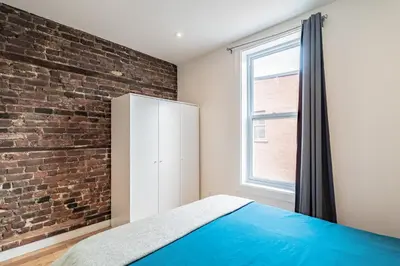 a bedroom with a brick wall and a white cabinet at Ideal Group Stay in Charming Le Plateau Near Metro in Montréal