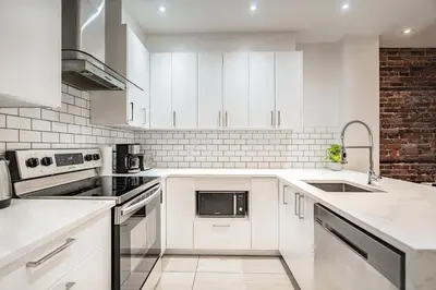 a white kitchen with white cabinets and appliances at Ideal Group Stay in Charming Le Plateau Near Metro in Montréal